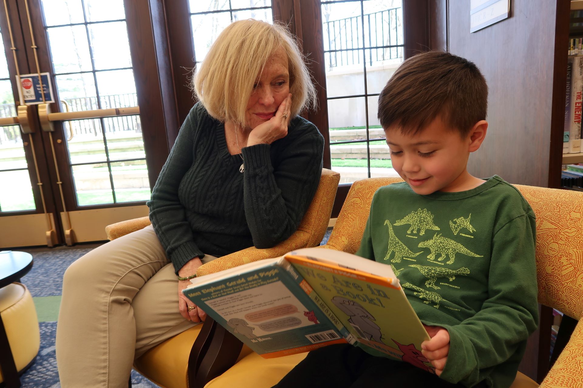 Adult woman reads with child in library.