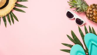Pink background with summer icons: straw hat, pineapple, sunglasses, and flip-flops