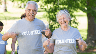 Senior man and woman point at their "volunteer" t-shirts