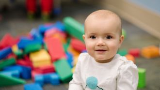 Baby with colorful blocks in the background.