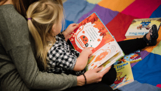 Child reads in the arms of her mother