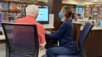 librarian and senior citizen working at public computers
