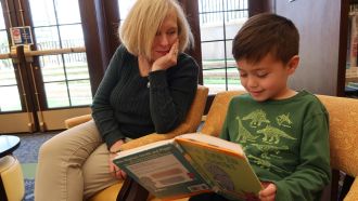Child reads at Wright Library with adult.