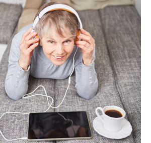 A woman listens to her tablet device with headphones.