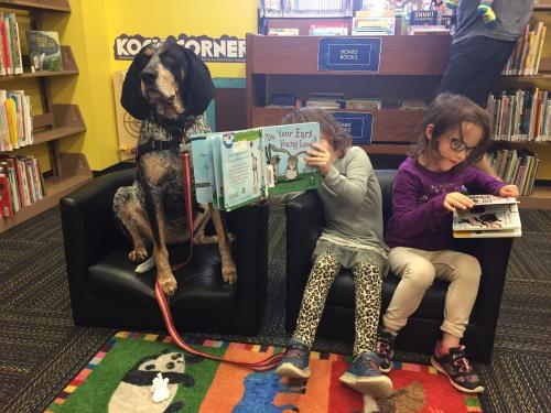 a little girl shows a long eared dog a page from book called "do your ears hang low"
